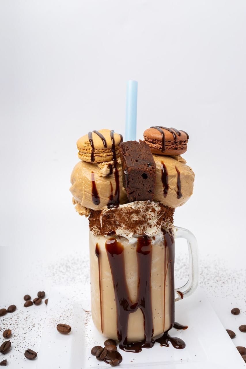 A loaded coffee milkshake topped with macarons and brownie