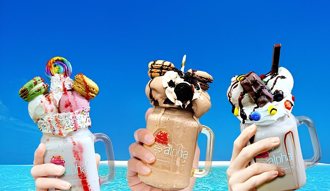 Three loaded Alpha Cafe milkshakes held up in branded jars